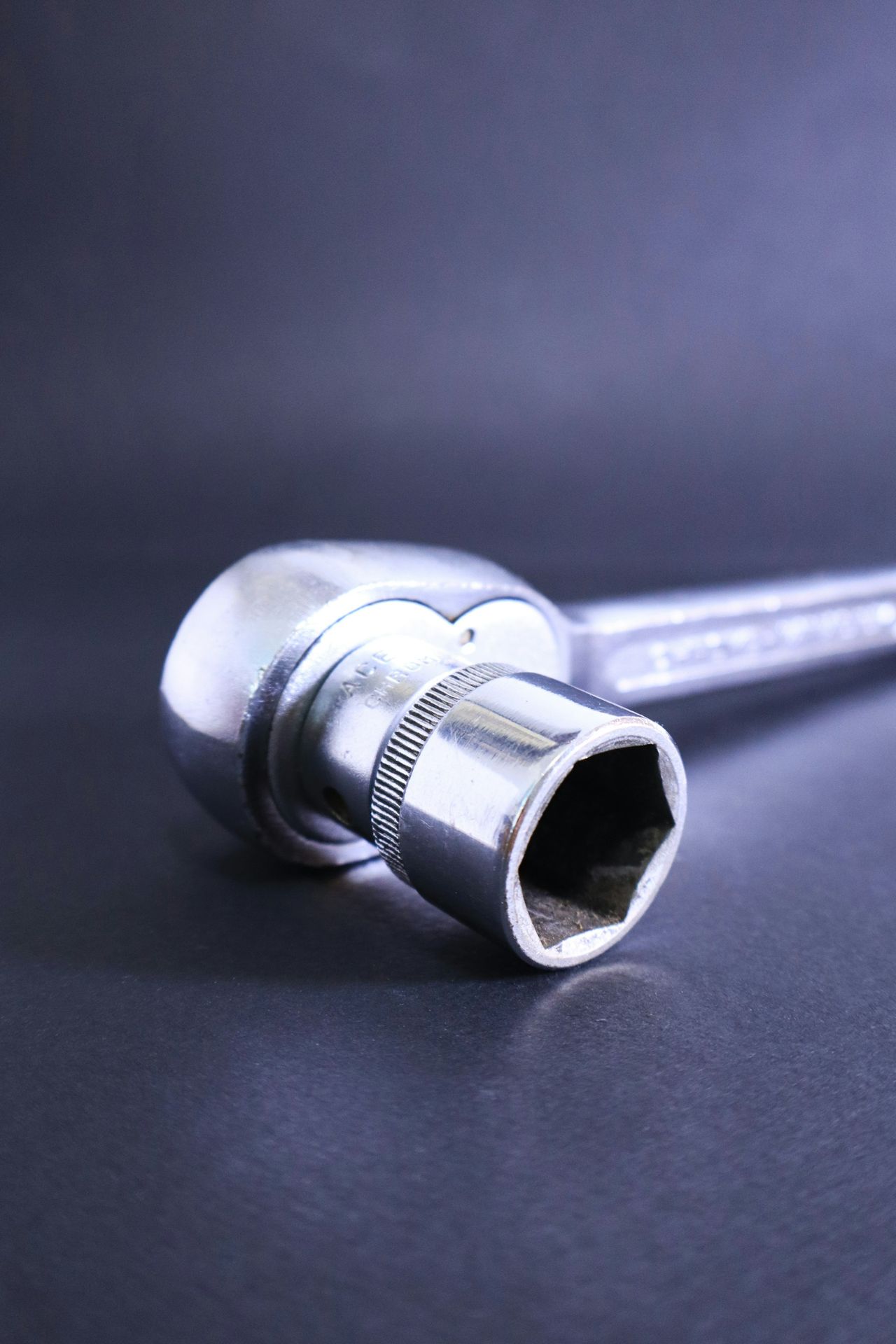 A socket wrench rests against a dark background.